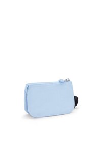 Involucro di tessuto blu chiaro con chiusura a zip. Presenta un accento in pom-pon nero. Forma rettangolare compatta con texture liscia.