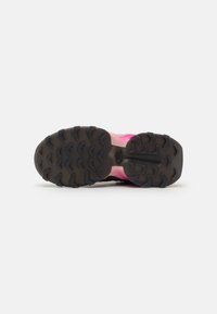 Semelle de chaussure de trail running en caoutchouc noir texturé avec de profondes larmiers pour la traction, se dégradant en rose sur le côté.
