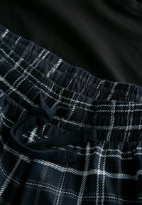 Černý bavlněný top nad námořnickými kostkovanými šortkami s bílými proužky. Šortky mají elastický pas a stahovací šňůrku pro úpravu velikosti.