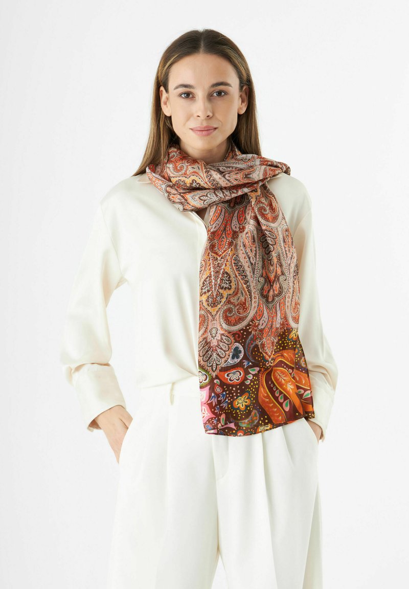 Zijden paisley sjaal met ingewikkelde oranje, rode en paarse patronen. Zachte textuur, valt elegant, gecombineerd met een crèmekleurige blouse.