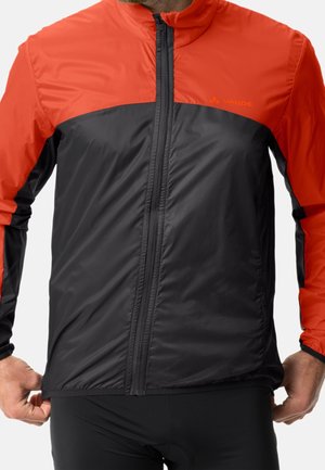 Leichte Jacke in Rot und Schwarz mit einem Reißverschluss vorne, hohem Kragen und langen Ärmeln. Glatte Textur mit kontrastierendem Farbblockdesign.