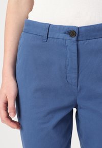Blue cotton trousers with a smooth texture, featuring a front button closure and a standard waistband, visible stitching details.