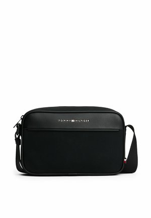 Sac messager noir en matériau synthétique, avec un devant lisse semblable au cuir, une poche zippée, une sangle réglable et un accent de logo.