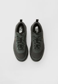 Mørkegrå sneakers med et teksturert stoffoverdel, snøring og polstret krage. Har en logo på innersålen og en slitesterk gummisåle.