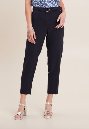 Pantaloni tapered blu navy realizzati in tessuto testurizzato, dotati di passante per cintura con anello in argento e tasche laterali. Indossati con sandali con tacco a blocco in argento.