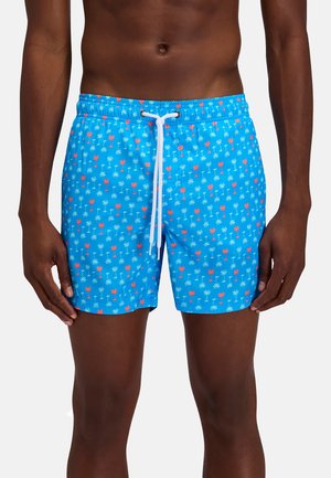 Costume da bagno blu con motivi di palme rosse e bianche indossato da una persona, con un laccio bianco annodato in vita.