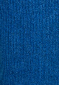 Blått stickat tyg med ett strukturerat ribbmönster. Färgen är en livlig, djup blå, med ett mjukt, varmt utseende.