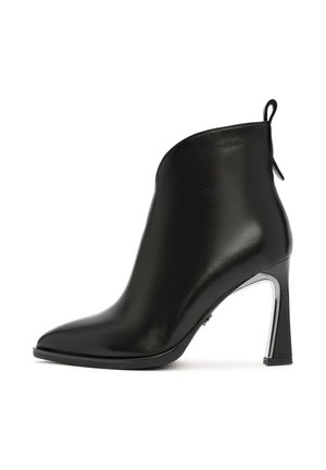 Zwarte leren enkellaars met een spitste neus, gebogen bovenkant en een metalen hak. Voorzien van een trekstrip aan de achterkant.