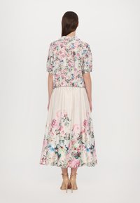 Floral print dress and cropped jacket in light fabric; features pink, white, and blue flowers. Pleated skirt reaches mid-calf, soft texture.