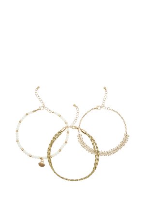 Three gold-tone adjustable bracelets, one twisted metal, one beaded with small white beads and charm, and one with tiny white flowers.