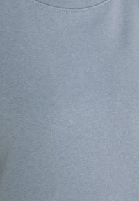 Ljusblå t-shirt, rund halsringning, mjukt bomullsblandat tyg, slät textur, minimal sömdetalj och inga synliga mönster eller grafik.