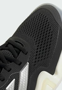 Μαύρο αθλητικό παπούτσι με υφασμάτινο επάνω μέρος με υφή, λεία διακοσμητικά στοιχεία και καουτσούκ σόλα. Διαθέτει ανακλαστικό ασημί λογότυπο και μαύρα κορδόνια.