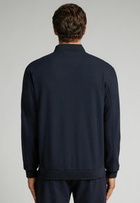 Marineblauwe sweatshirt met een ribgebreide kraag en manchetten, gemaakt van een gladde stof. Het heeft een eenvoudig ontwerp zonder zichtbare logo's of patronen.