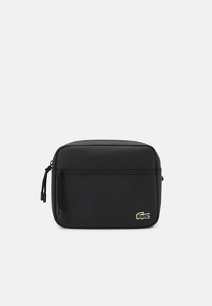 Bolso rectangular negro hecho de material texturizado, con un bolsillo frontal con cremallera y un logo bordado en verde como detalle.