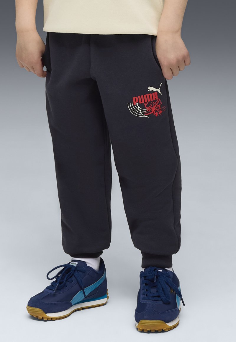 Ciemnoszare dresy z czerwonym logo i grafiką Puma, ze ściągaczami na kostkach. W zestawie z granatowymi trampkami z jasnoniebieskimi akcentami.