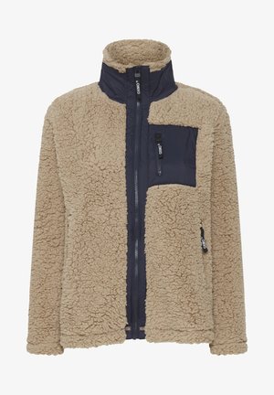 Fleecejakke med en beige teksturert overflate og marineblå nylon frontpaneler. Har høy krage og glidelås lomme på brystet.