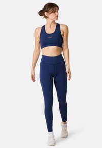 Granatowy stanik sportowy i legginsy o wysokim stanie wykonane z elastycznej tkaniny. Stanik ma okrągły dekolt, a legginsy charakteryzują się bezszwowym designem dla większego komfortu.