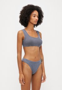 Grå ribbad bralette och hipster-kalsongset. Funktioner inkluderar en rundad halsringning och elastisk midja. Mjuk tygkvalitet med minimala sömnadsdetaljer.