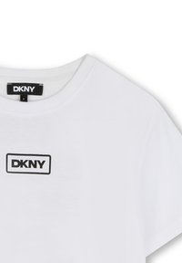 Witte katoenen t-shirt met een ronde hals en korte mouwen. Heeft een zwart rechthoekig DKNY-logo in het midden van de borst. Soepele textuur.