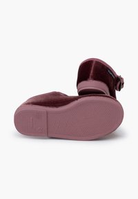 Zuecos de terciopelo burdeos con punta redonda, hebilla ajustable y suela de goma texturizada. Material suave y diseño de tacón redondeado.