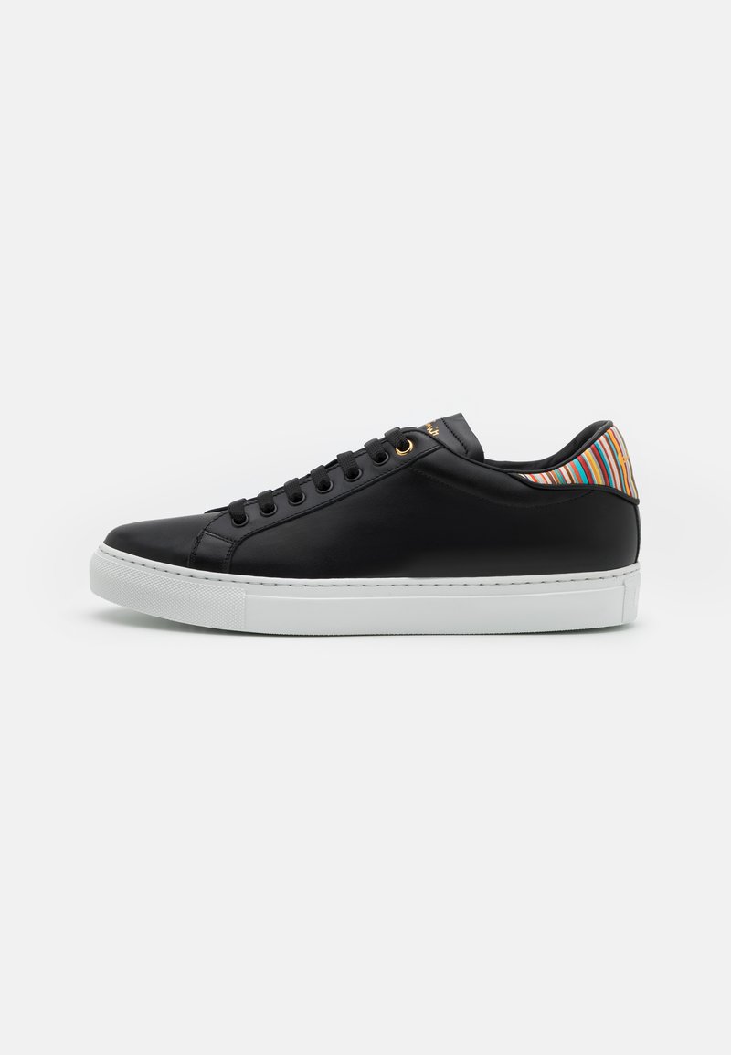 Black leather sneaker with a white rubber sole, featuring a striped multicolor accent on the heel and black lace-up front with gold eyelets.