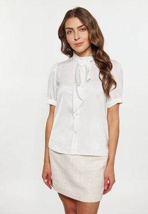 Witte blouse met korte mouwen en een rimpelachtige nekstrik en knopenrij, gemaakt van gladde stof, gecombineerd met een lichtgekleurde, gedetailleerde rok.