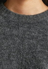 Maglione grigio in lana con finitura testurizzata, caratterizzato da una scollatura rotonda. Il tessuto appare morbido e accogliente, con una superficie leggermente pelosa.