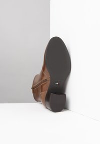 Braune Leder-Stiefelette mit einem seitlichen Reißverschluss, rechteckigem Absatz und strukturiertem Gummisohle. Verfügt über leichte Nähte und Branding auf der Sohle.