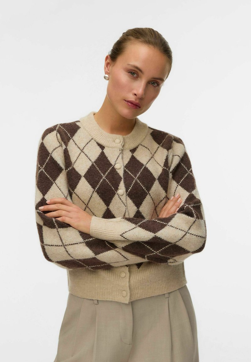 Cardigan argyle marrone e beige con chiusura a bottoni, polsini a coste e texture morbida. Stile con scollatura rotonda e vestibilità cropped.