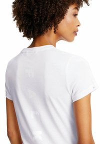 Weiße Baumwoll-T-shirt mit Rundhalsausschnitt und kurzen Ärmeln. Auf dem Rücken befindet sich der Text "FALK" in subtilen, strukturierten weißen Buchstaben.