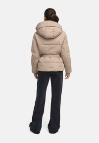 Beige gewatteerde jas met een grote capuchon, een cinched taille en een riemontwerp. De stof lijkt zacht en heeft gewatteerde secties en subtiele branding.