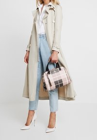 Beżowy trencz na białej koszuli, w połączeniu z jasnoniebieskimi dżinsami. Torba w kratę w odcieniach różu oraz czarne i białe szpilki dopełniają całość.