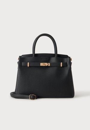 Sac à main en cuir noir texturé avec un fermoir doré, double poignées et une bandoulière réglable posé devant sur fond blanc.