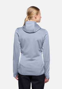 Lichtblauwe hoodie met lange mouwen, gestructureerde stof, aansluitend ontwerp en duimopeningen aan de manchetten. Achteraanzicht toont naaddetails.