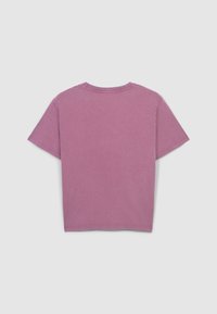 Vista posteriore di una maglietta di cotone rosa a maniche corte con collo a giro, caratterizzata da una texture leggermente sbiadita e dettagli di orlo grezzo.