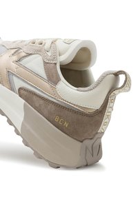 Sportschoenen in beige en lichtbruine tinten, met een mix van leer en suède, textuuraccenten en een gouden "BCN" logo op de hak.
