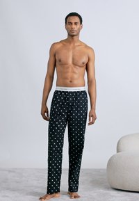 Μαύρο παντελόνι πυτζάμας με λευκά λουλουδάτα σχέδια, ελαστική μέση με το λογότυπο "Calvin Klein", ευθεία γραμμή ποδιού, μαλακή υφή υφάσματος.