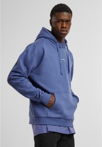 Felpa blu in cotone con tasca a marsupio, cappuccio con cordino e piccolo logo bianco sul petto. Presenta una vestibilità comoda e un tessuto testurizzato.