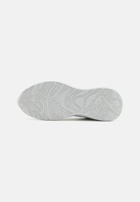 Suela de zapatilla blanca con un patrón texturizado. Forma redondeada, material flexible y surcos profundos para tracción. Diseño limpio y minimalista.