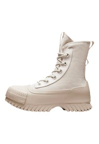 Botas altas blancas con parte superior de lona, puntera de goma, suela texturizada y ojetes metálicos con cordones. Bucles laterales para facilitar el uso.