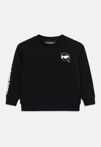 Μαύρο παιδικό φούτερ με μακριά μανίκια, με μικρό λευκό καρτούν πρόσωπο που φοράει γυαλιά ηλίου στο στήθος και λευκό κείμενο στο αριστερό μανίκι.