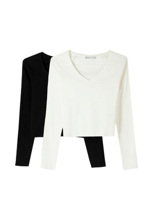 Deux tops à manches longues en v, l'un noir et l'autre blanc, fabriqués en tissu doux, au design court, avec des fentes latérales pour le style et le confort.