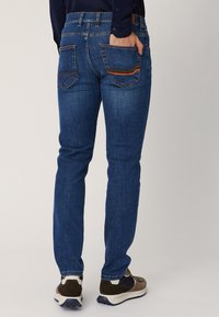 Ciemnoniebieskie d�żinsy w slim fit, z dwoma tylnymi kieszeniami z kontrastującymi paskami i delikatnie wyblakłą fakturą.