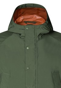 Vihreä eristetty takki, jossa on korkea kaulus, vetoketjusuljenta, nappikiinnitys ja oranssi vuori. Sisältää sivutaskut.