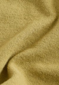 Tissu texturé jaune avec un motif de tricot subtil, offrant une apparence douce et chaude ainsi qu'une surface légèrement floue et pelucheuse.