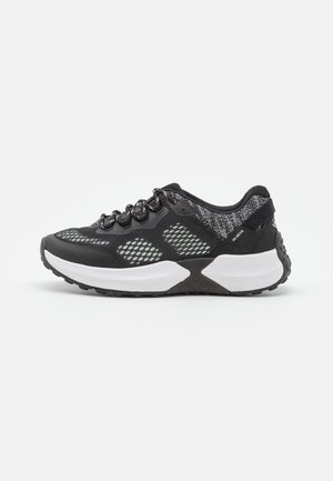Zapatilla deportiva negra con paneles de malla, cordones redondos y suela media blanca. Suela exterior texturizada con características de amortiguación y detalles reflectantes.