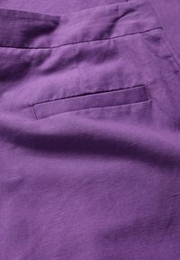 Fioletowa tkanina o gładkiej strukturze i subtelnej połysku, z jedną kieszenią i starannie wykończonym brzegiem.