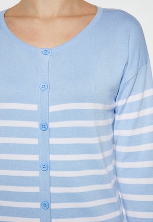 Vaaleansininen neuletakki, jossa on valkoisia vaakasuoria raitoja. Tässä on V-pääntie ja kuusi sinistä nappia edessä. Sileä, neulottu rakenne.