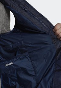 Interior de chaqueta de marina desmontable con material suave y ligero. Cuenta con un bolsillo con cremallera y una etiqueta bordada de "desmontable".