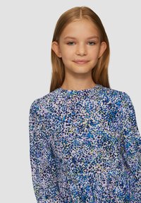 Sukienka w kwiatowy wzór w odcieniach niebieskiego, fioletowego i zielonego. Długie rękawy, okrągły dekolt i marszczona talia, tworzące zwiewny kształt.